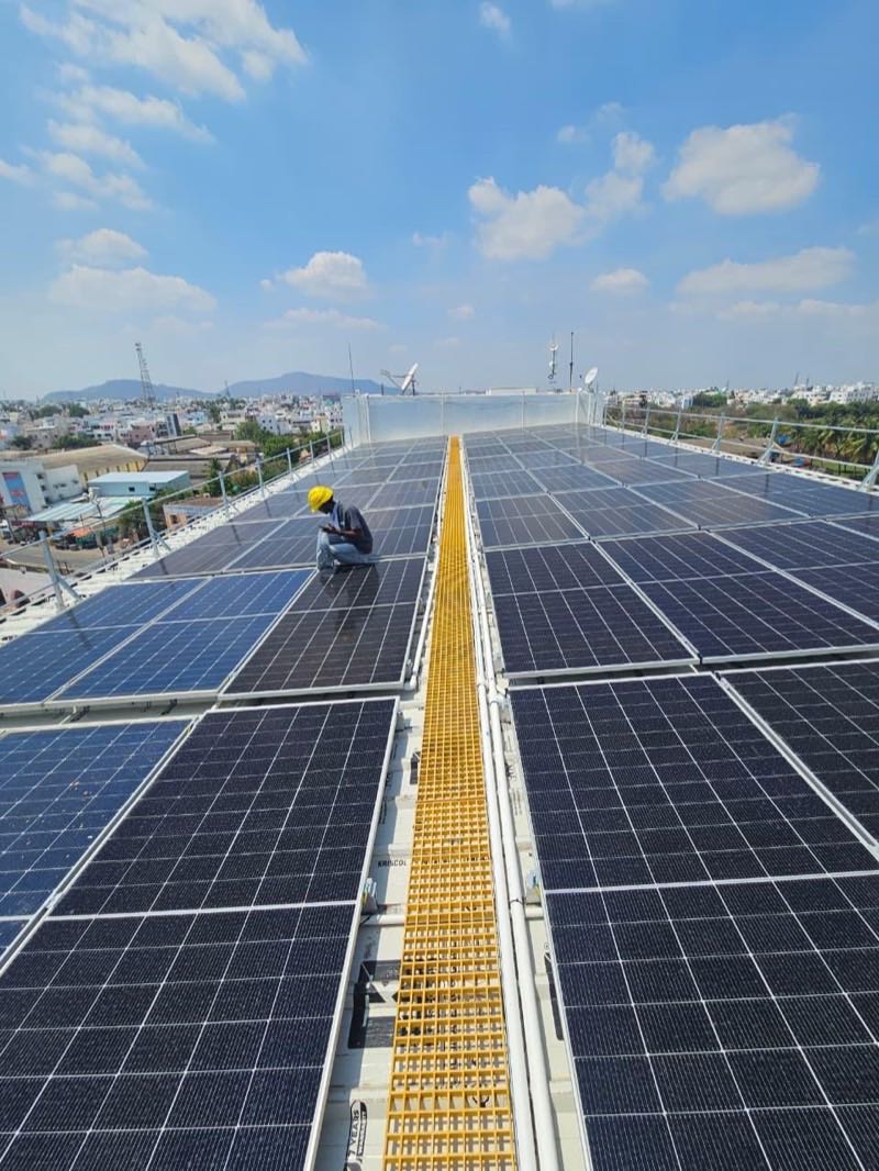 Technician inspecting an industrial rooftop solar array
